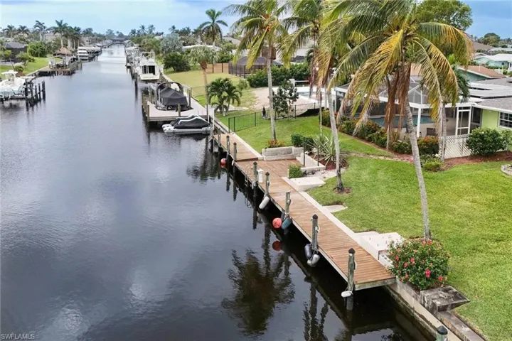 View of dock featuring a yard, a water view, and glass enclosure