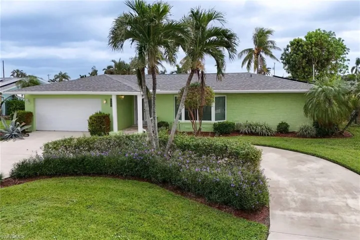 Single story home featuring a front yard, circular driveway and a garage