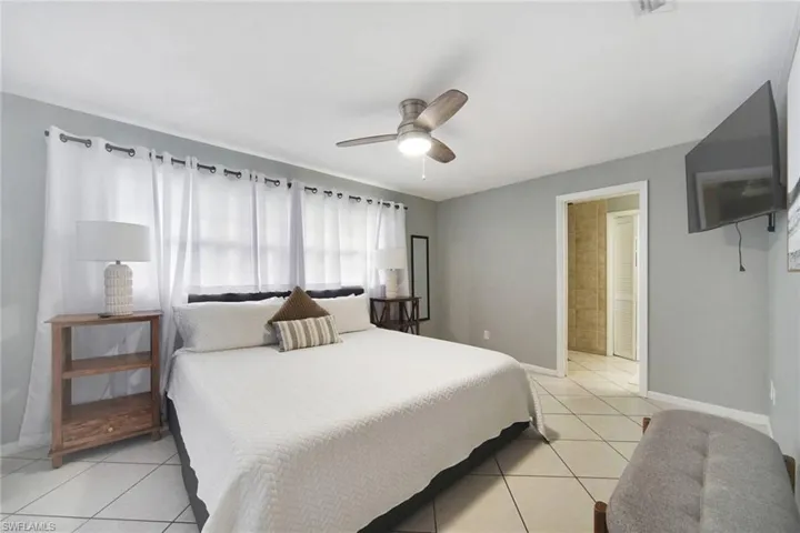 Tiled primary bedroom with ceiling fan and in suite bath.