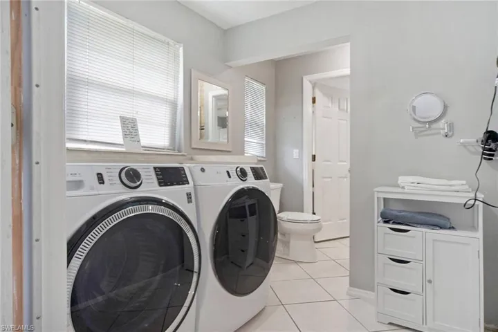 Clothes washing area featuring separate washer and dryer and light tile patterned flooring