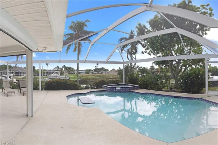 View of swimming pool featuring an in ground hot tub, a water view, a lanai, and a patio area
