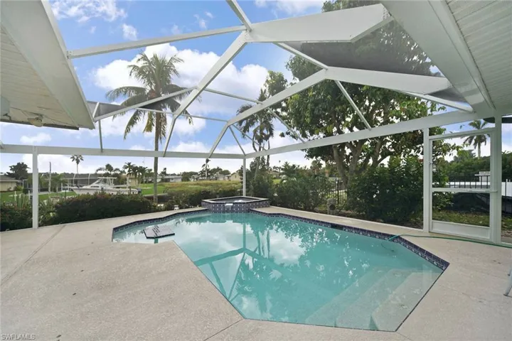 View of pool with wide open screen design and heated spa and waterfall.