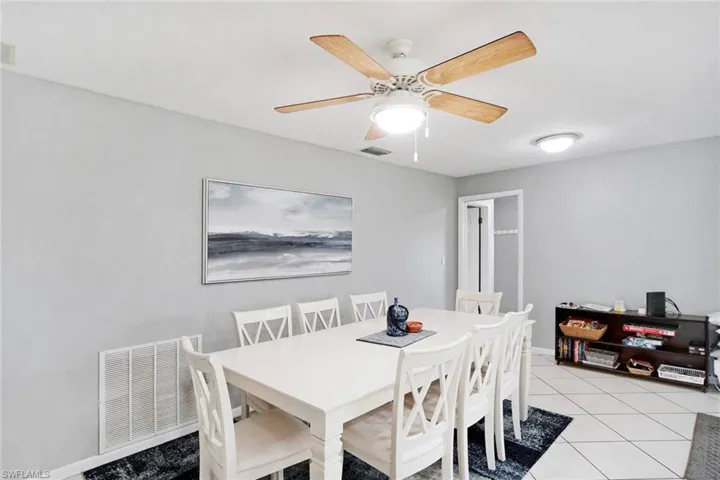 Spacious Dining area with ceiling fan and light tile patterned floors with sliding glass out to pool area.