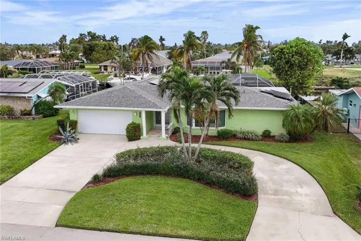 View of front of home featuring a lanai, a front lawn, and a garage