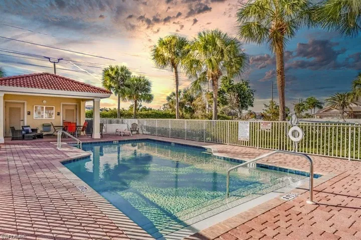 Pool at dusk with a community pool, fence, and a patio