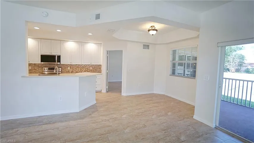 Kitchen with white cabinets, stainless steel appliances, tasteful backsplash, and visible vents