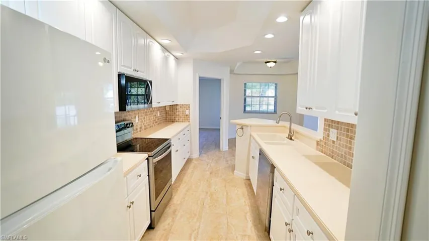 Kitchen with a sink, white cabinetry, tasteful backsplash, stainless steel appliances, and recessed lighting