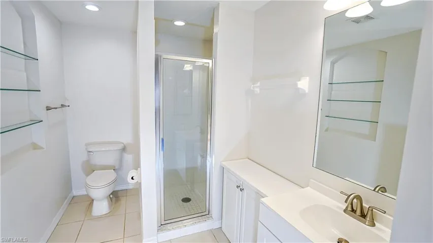 Full bathroom with visible vents, a shower stall, toilet, vanity, and tile patterned flooring