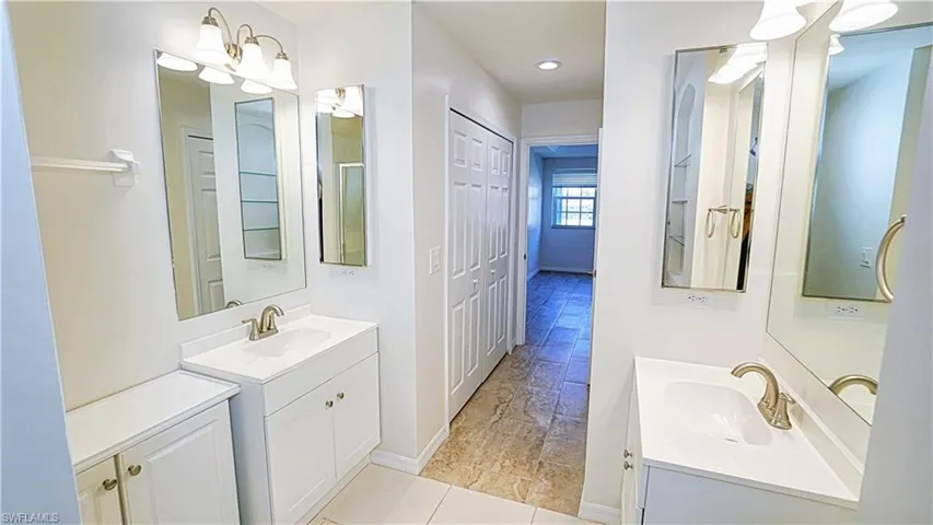 Full bath with a sink, two vanities, and baseboards