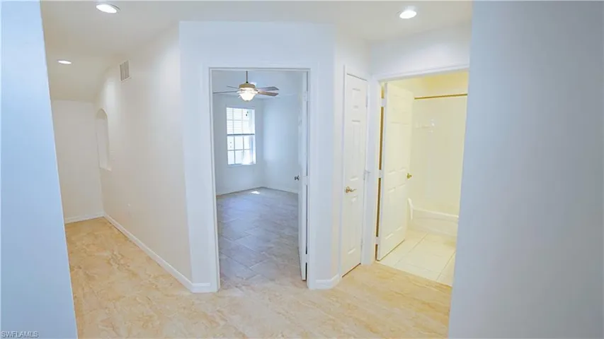 Corridor featuring recessed lighting, arched walkways, baseboards, and visible vents