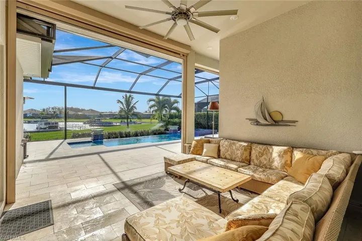 View of patio featuring outdoor lounge area, glass enclosure, ceiling fan, and a water view