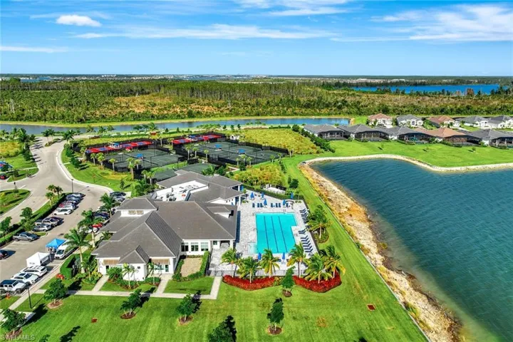Pool at dusk with a patio, a water view, and a lanai
