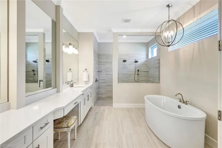 Bathroom with vanity, an inviting chandelier, ornamental molding, and separate shower and tub