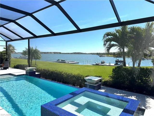 View of pool featuring a patio area, glass enclosure, a yard, and a water view