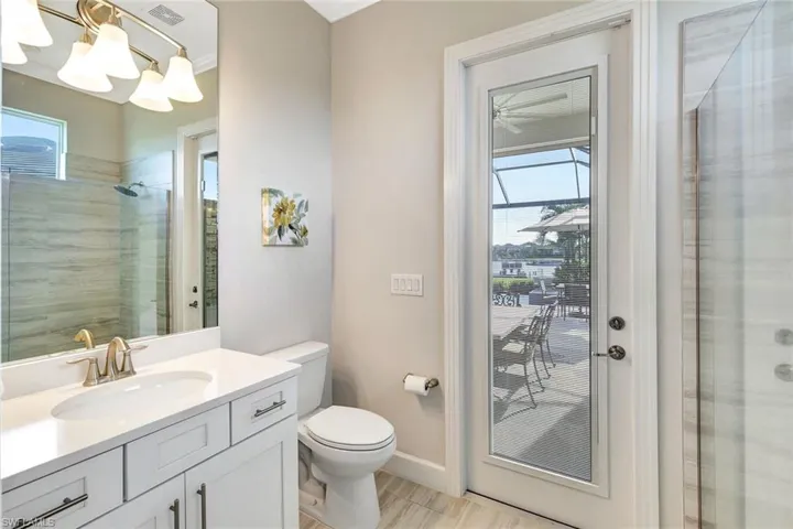 Bathroom with a tile shower, vanity, a chandelier, and toilet