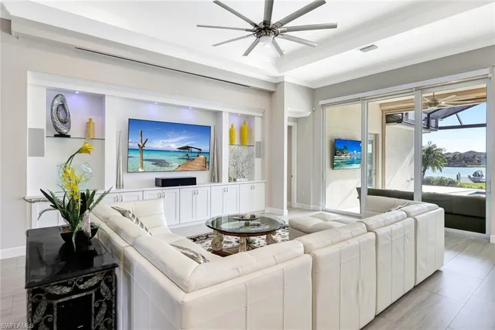 Living room with a tray ceiling, ceiling fan, crown molding, and light hardwood / wood-style floors