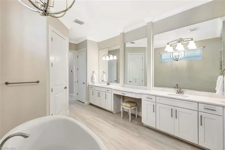 Bathroom featuring ornamental molding, vanity, a bath, wood-type flooring, and a notable chandelier