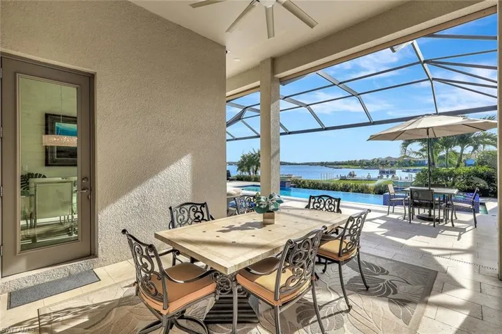 View of patio with a lanai, ceiling fan, and a water view