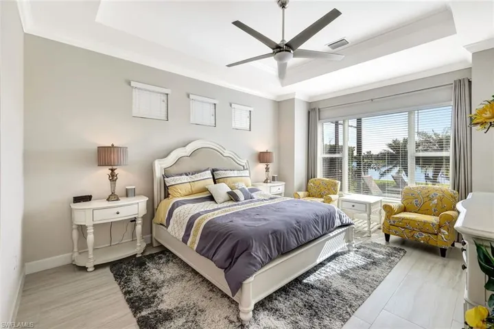 Bedroom with a raised ceiling, ceiling fan, and ornamental molding