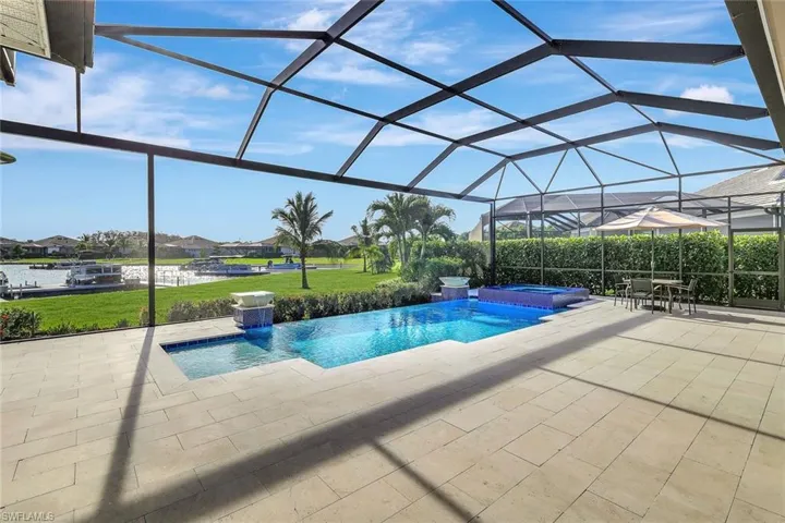 View of pool featuring a lawn, glass enclosure, pool water feature, an in ground hot tub, and a patio