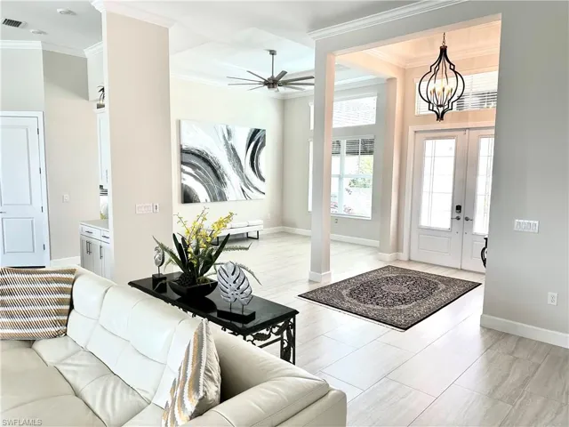Entrance foyer featuring french doors, ceiling fan with notable chandelier, baseboards, and ornamental molding