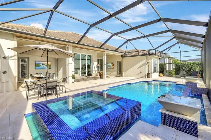 View of swimming pool with pool water feature, a patio area, a lanai, and an in ground hot tub
