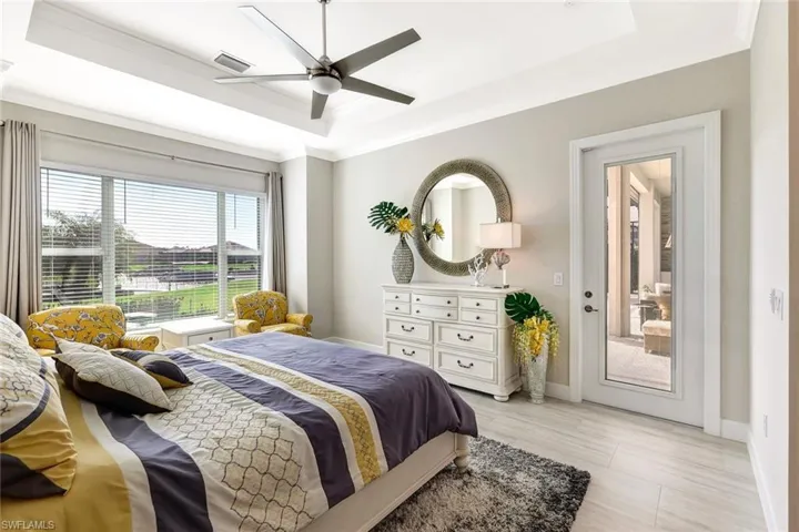 Bedroom with a tray ceiling, ceiling fan, and ornamental molding
