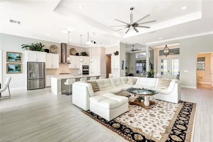 Living room with ceiling fan with notable chandelier, light hardwood / wood-style floors, a raised ceiling, and ornamental molding