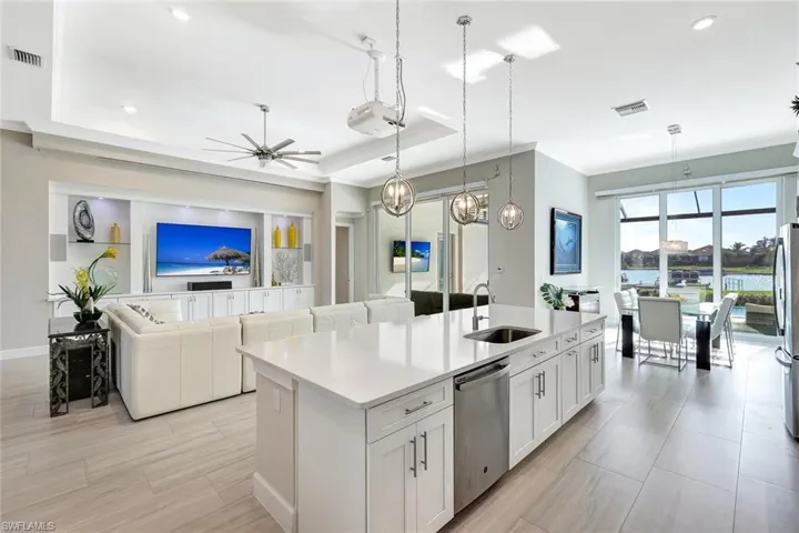 Kitchen featuring pendant lighting, a center island with sink, white cabinets, stainless steel dishwasher, and ceiling fan
