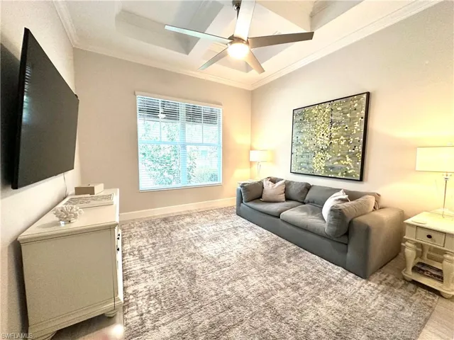 Living room with carpet flooring, crown molding, a ceiling fan, and coffered ceiling