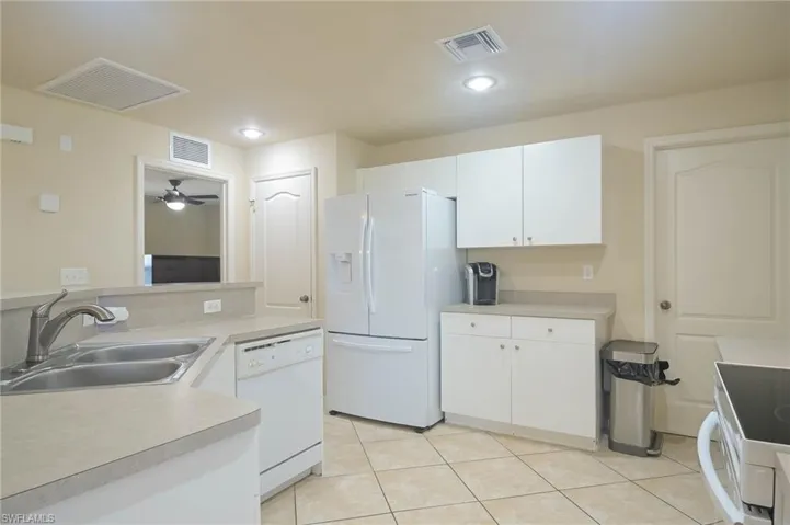 Kitchen featuring sink, white cabinets, white appliances, and light tile patterned floors