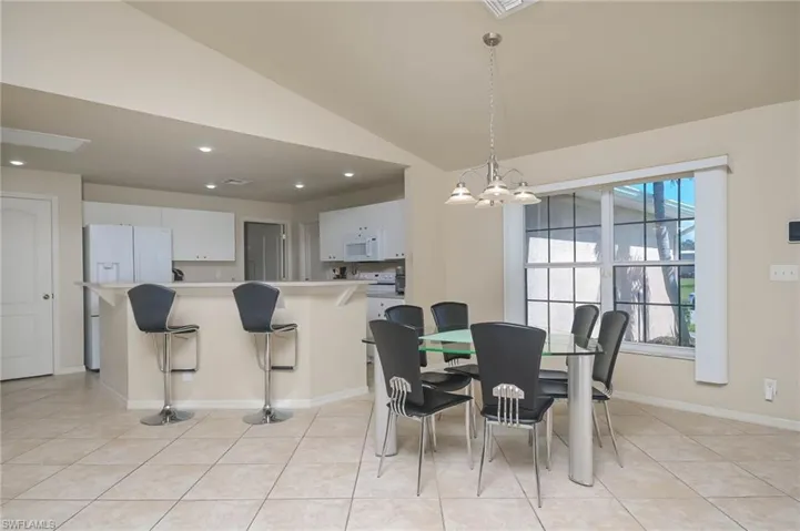 Dining room featuring a chandelier, vaulted ceiling, and light tile patterned floors