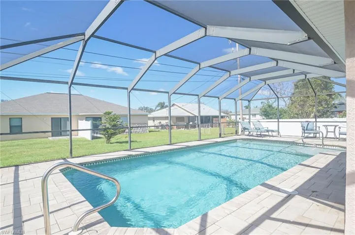 View of pool with a patio, a lawn, and glass enclosure