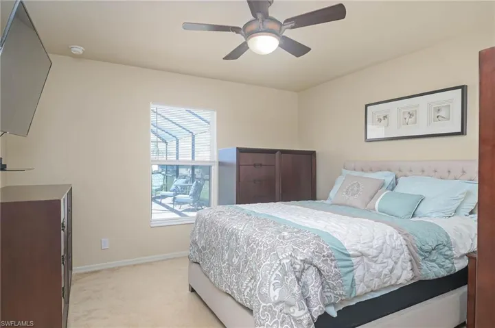 Bedroom with ceiling fan and light colored carpet