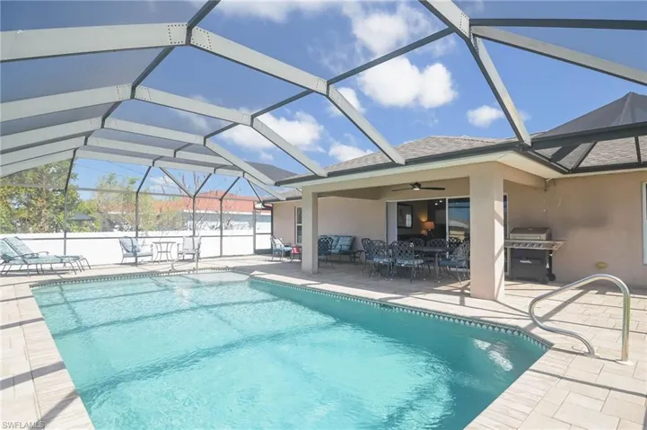 View of pool featuring a patio, ceiling fan, grilling area, and glass enclosure