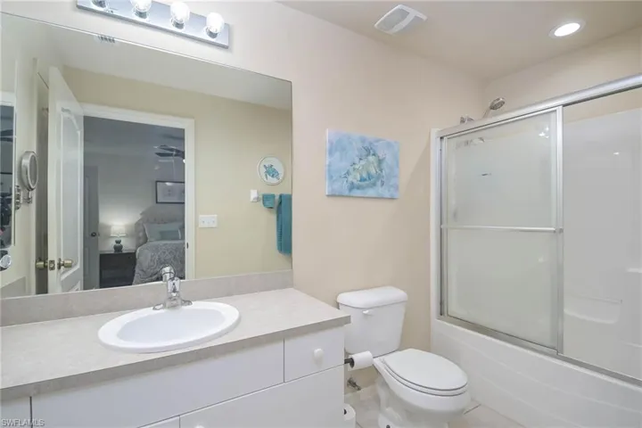 Full bathroom featuring vanity, toilet, tile patterned floors, and enclosed tub / shower combo