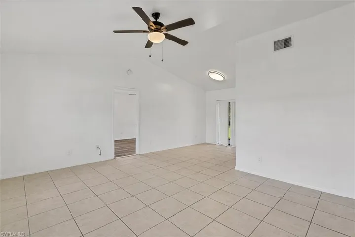 Unfurnished room with lofted ceiling, light tile patterned floors, and ceiling fan