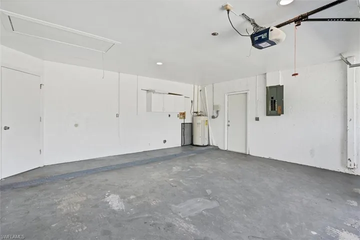 Garage featuring water heater, a garage door opener, and electric panel