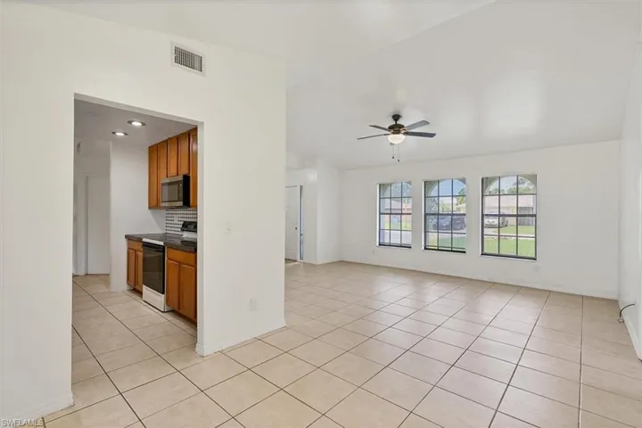 Kitchen featuring decorative backsplash, light tile patterned flooring, white electric range oven, and ceiling fan