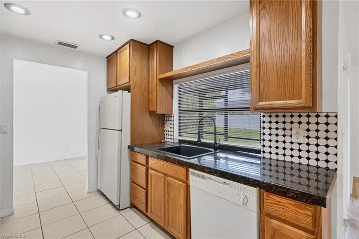 Kitchen with tasteful backsplash, white appliances, sink, and light tile patterned flooring