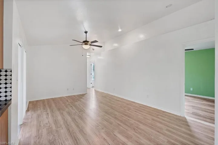 Unfurnished room with ceiling fan, lofted ceiling, and light hardwood / wood-style floors