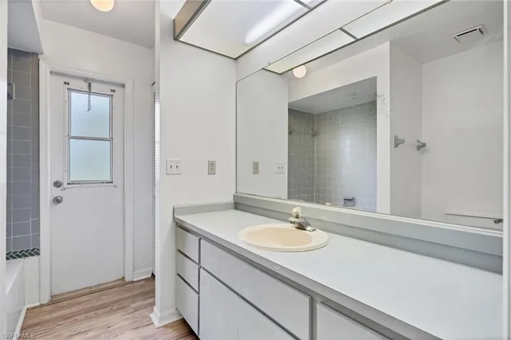 Bathroom featuring tiled shower / bath, vanity, and hardwood / wood-style floors