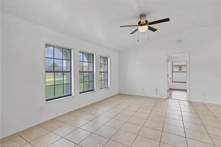 Spare room featuring ceiling fan, light tile patterned flooring, and lofted ceiling