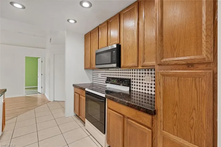 Kitchen featuring tasteful backsplash, dark stone countertops, white electric stove, and light hardwood / wood-style floors