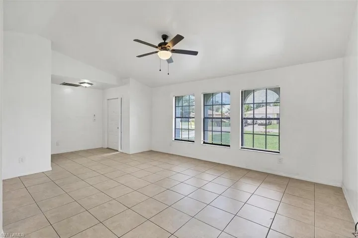 Tiled empty room with lofted ceiling and ceiling fan