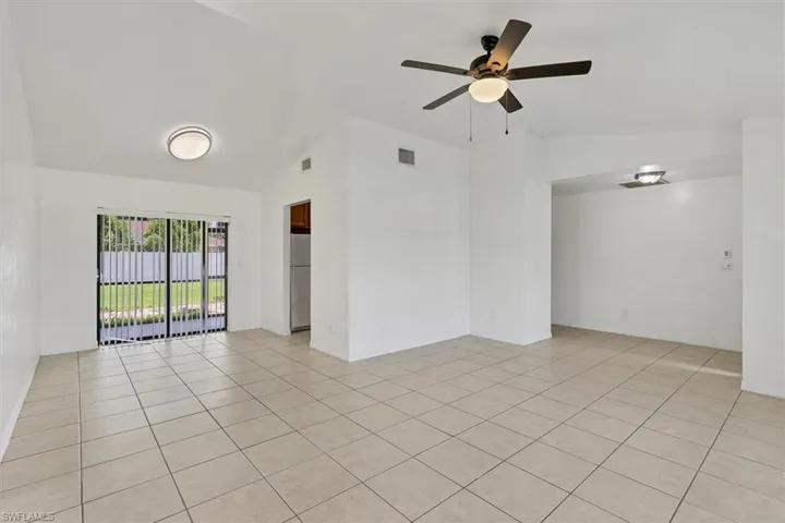 Unfurnished room featuring lofted ceiling, light tile patterned flooring, and ceiling fan