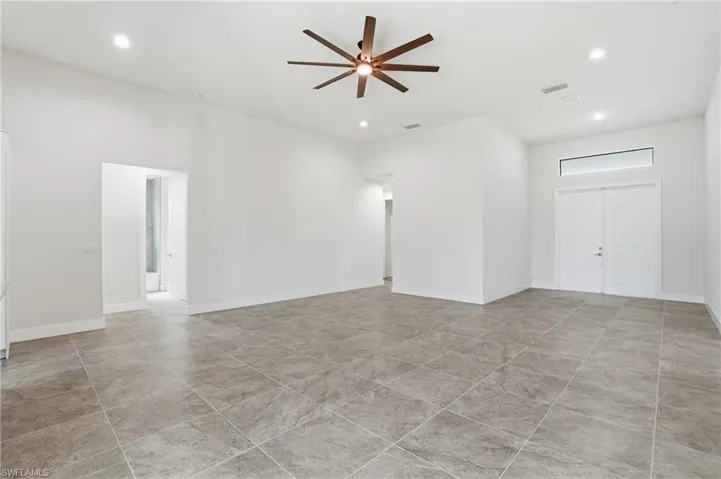 Spacious interior featuring large format tile flooring, high ceilings with recessed lighting, and a modern ceiling fan