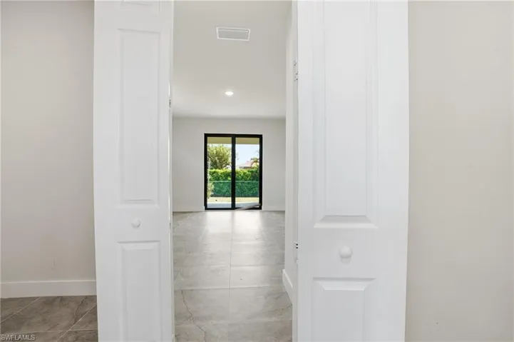 Interior space featuring neutral-toned tile flooring throughout, white walls, and recessed lighting