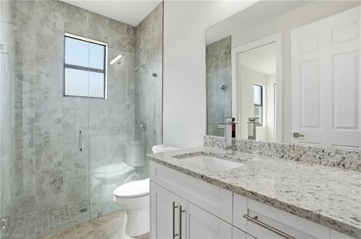 Contemporary bathroom featuring a spacious glass-enclosed shower with gray tiled walls and a window