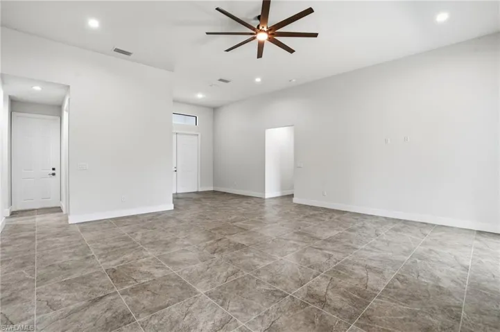 Spacious interior featuring large format tile flooring, high ceilings, recessed lighting, and a modern ceiling fan